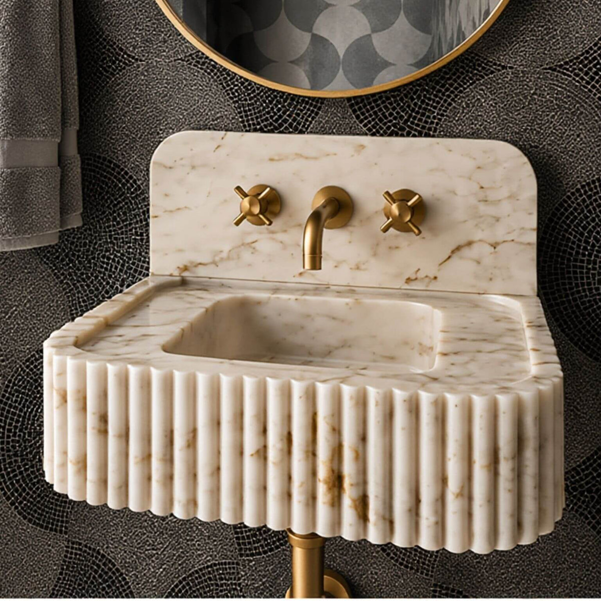 Angled view of a Calacatta Gold marble sink and matching backsplash, showing continuous grey and gold veining across the natural stone.