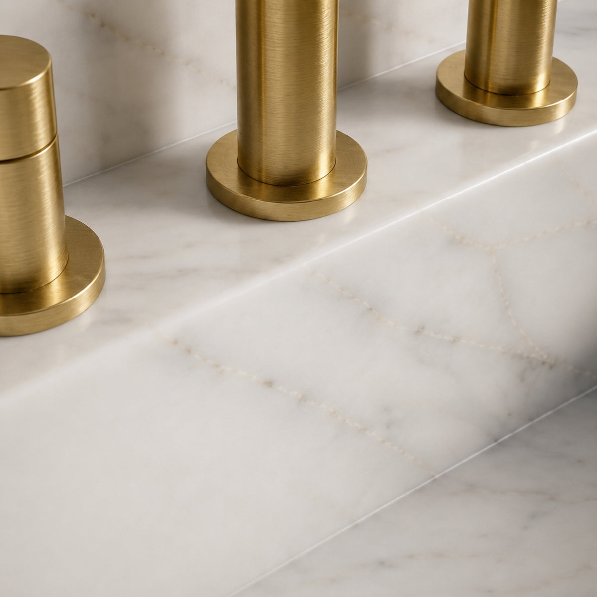 Carrara White marble wall-mounted sink with fluted detailing, integrated high backsplash, and a brushed gold faucet set.